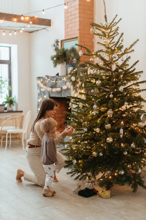 mom and child hanging ornament on Christmas tree