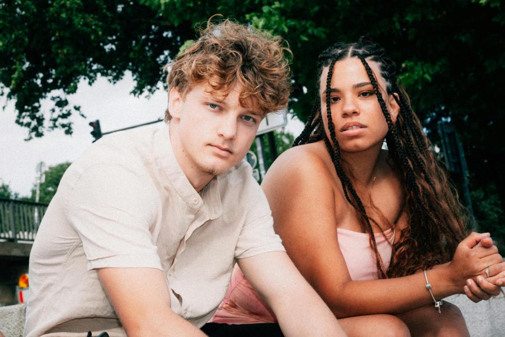 A young white man and young black woman sit by each other outside as they contemplate filing a no-fault divorce.