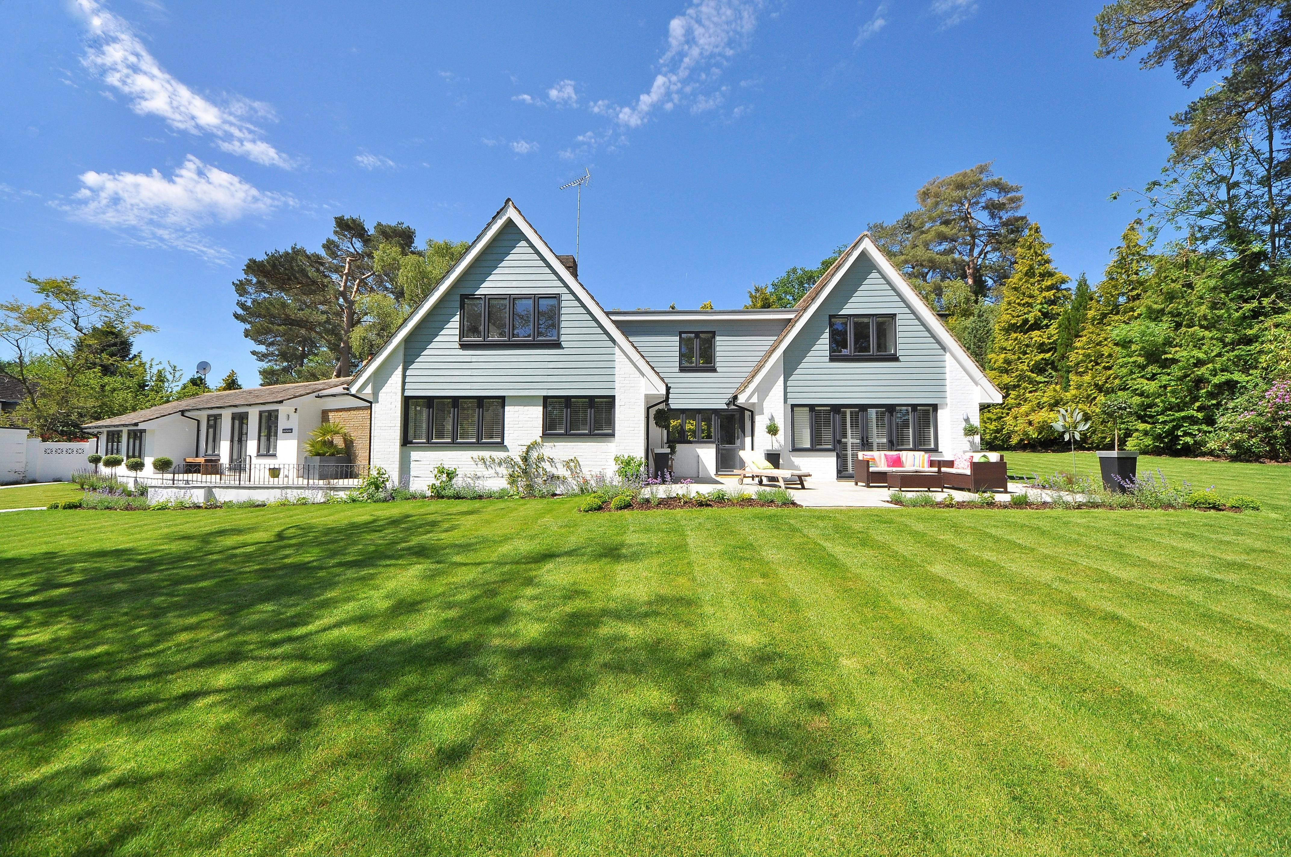 A large family home sits on a green lawn.