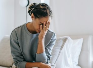 A young black woman has her head in her hands as she deals with the strain of divorce