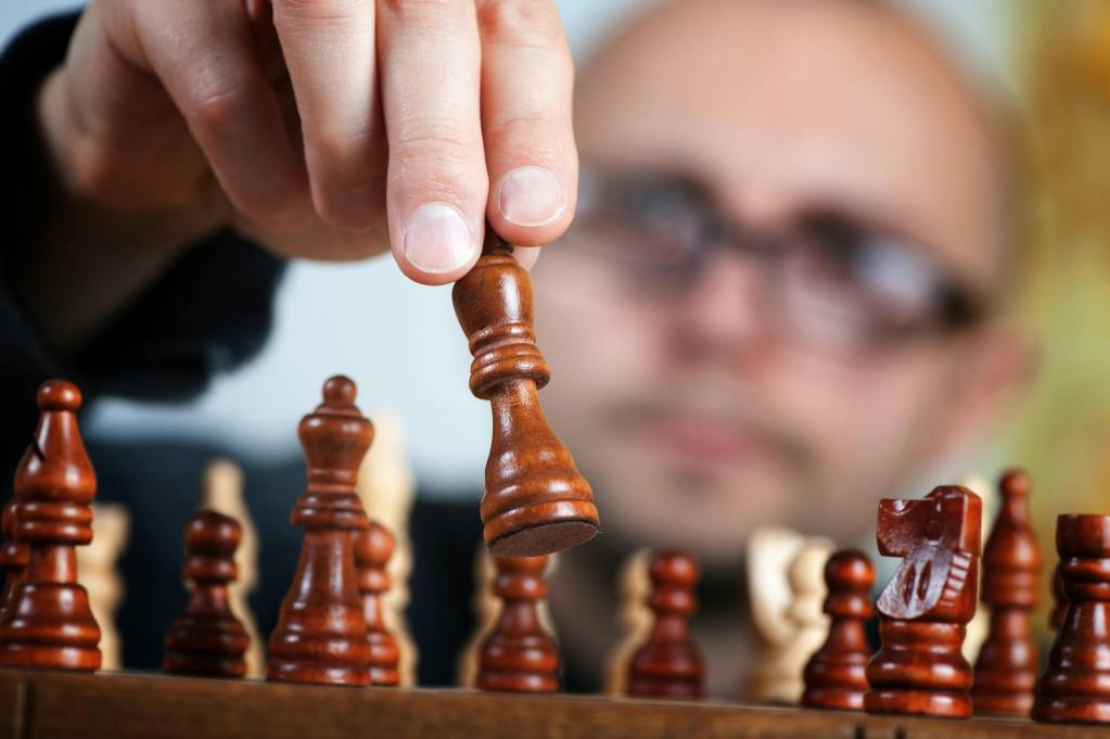 A man is moving a chess piece on the chess board